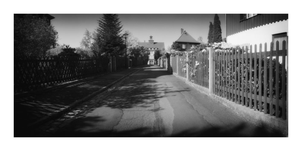 Straßenflucht mit querstehendem Schulgebäude am Ende.