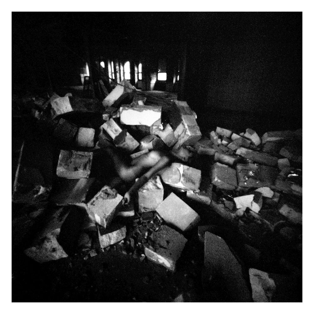 Nacktes Model auf einem Trümmerberg liegend.