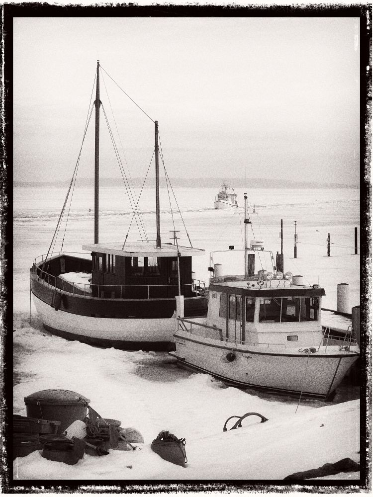 Fischkutter am Steg im vereisten Wasser.