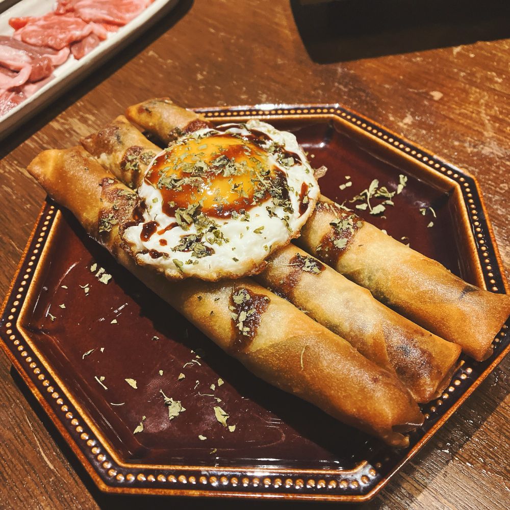 目玉焼きが乗せられた春巻（3本）の写真