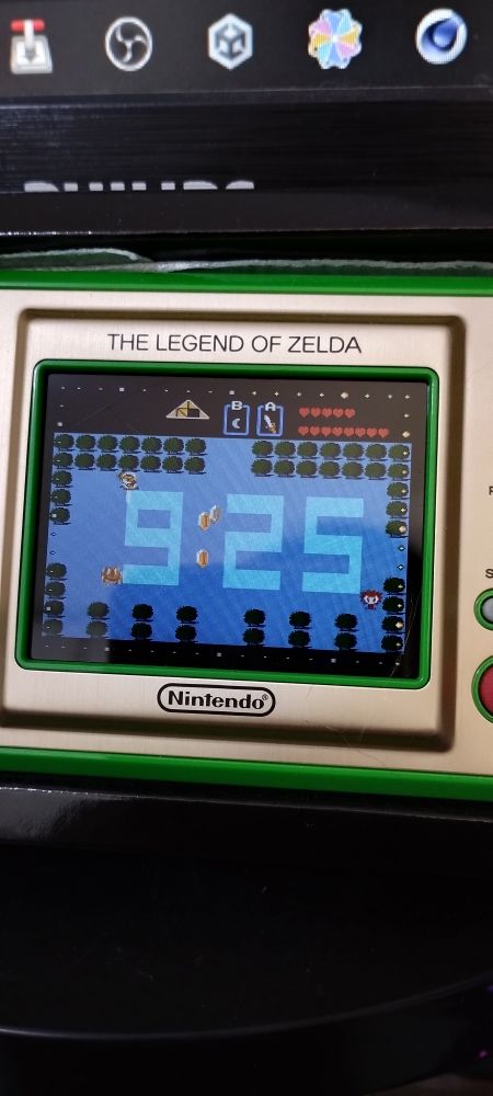Picture of the Zelda Game & Watch sitting on my table, showing Link playing the game automatically around the clock. 