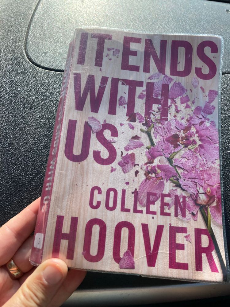 Book cover of It Ends With Us by Colleen Hoover depicting damaged pink lilies.