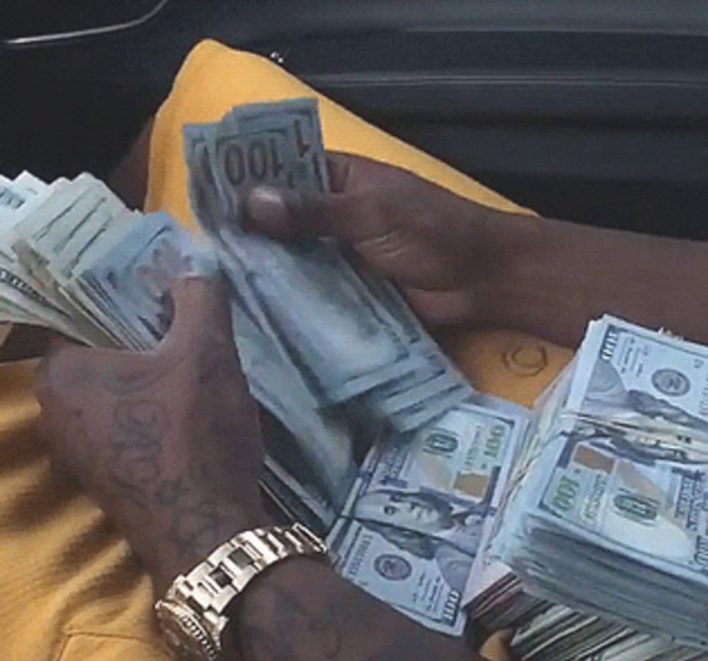 a man is holding a stack of 100 dollar bills in his hands