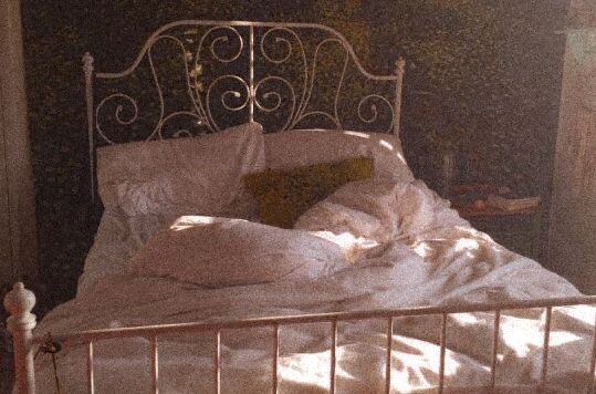aesthetic image of an unmade bed with a fancy headboard/frame