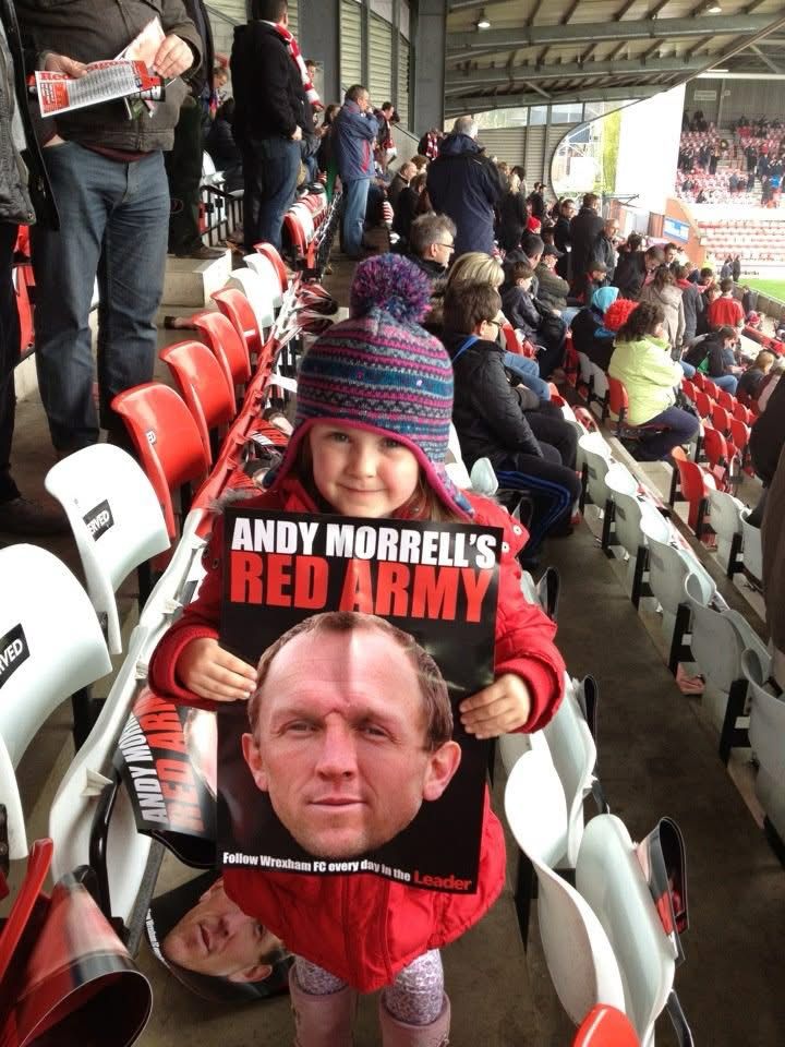 Young girl holding a poster with a picture of Andy Morrell on it. 