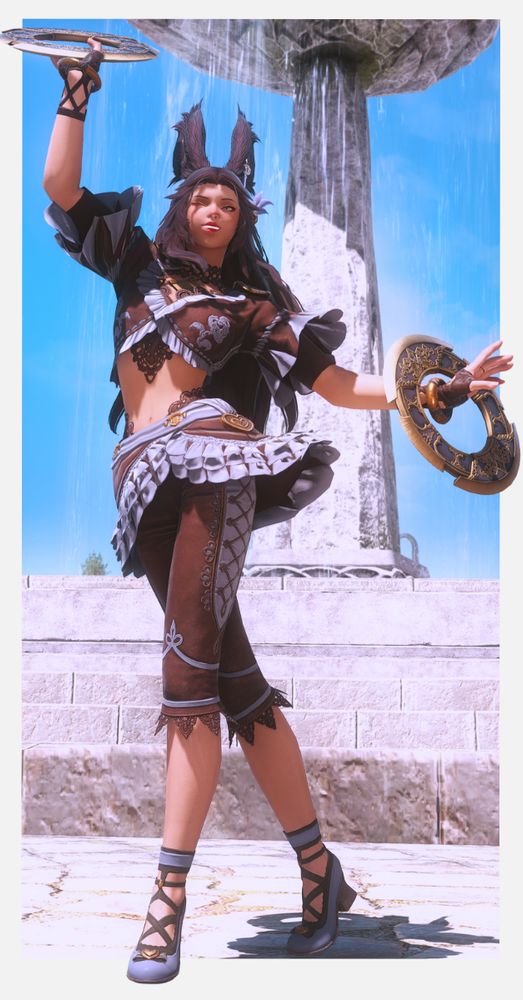 A viera woman is in the front and center of the picture, she is wearing Dancer attire, and is posing with her two chakrams. She is smiling and winking towards the camera as she poses. There is a clear blue sky and water fountain behind her. 