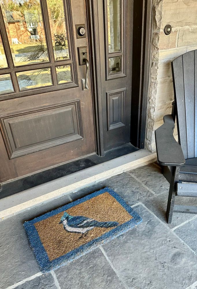 Photo of front porch with a welcome mat  depicting a blue jay. 