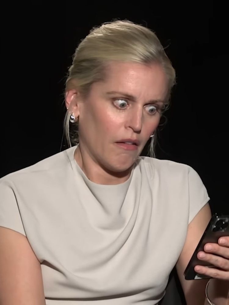 woman staring at her phone in utter horror