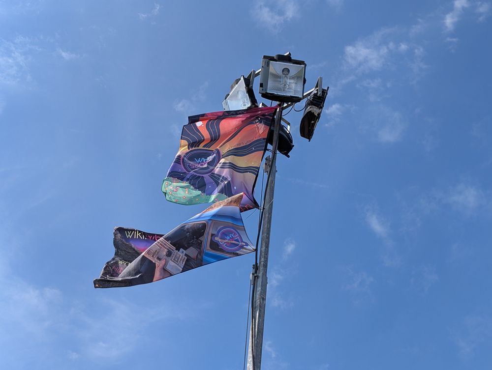 The WHY flag and shuttle flag below, blowing in the wind from the light tower 