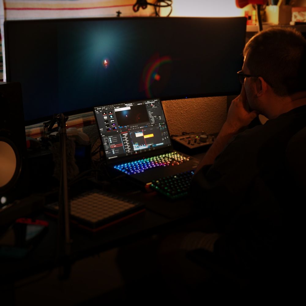 modus is seen in his studio working on the animation film for 'New Year Protocol X: The End'. He is sitting down, hands holding his chin as he looks at the visual effects for the part he is working on through his computer monitors.
