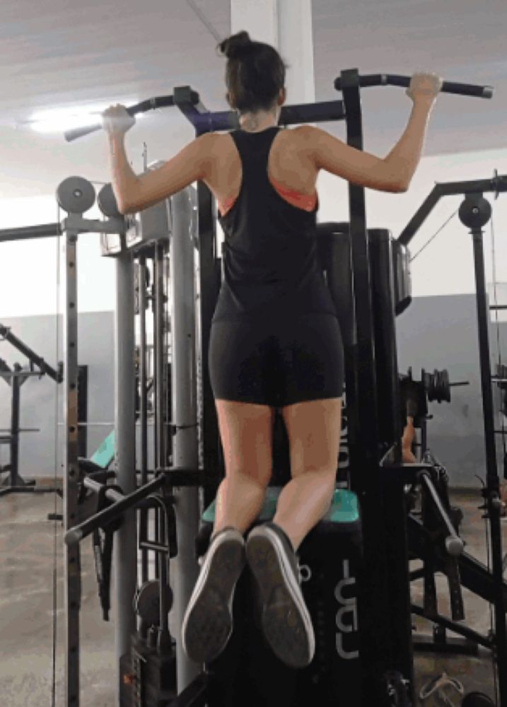 a woman is doing a pull up in a gym with a machine that says ucd