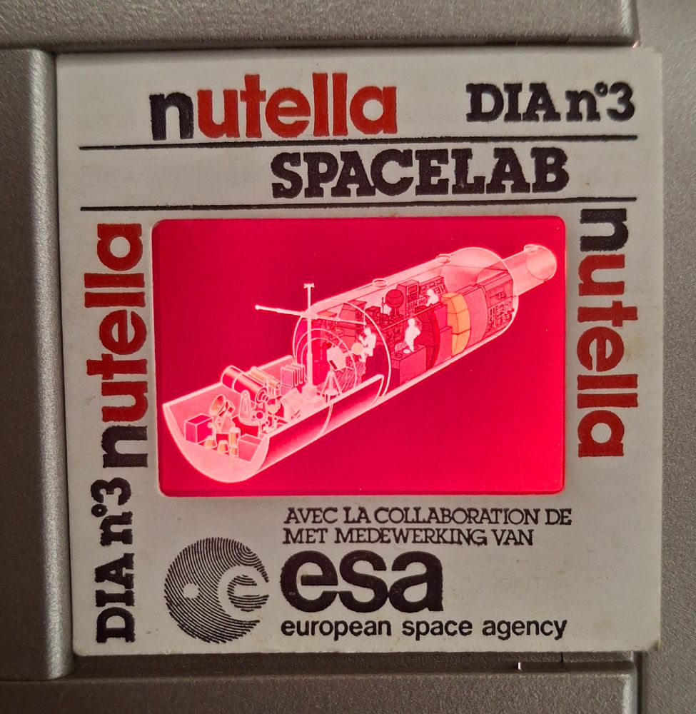 A slide showing a cut-through view of a spacelab. On the border of the slide, the brand 'Nutella' is mentioned three times. The slide was number 3 in a series on space research, made in collaboration with ESA, the European Space Agency (as also indicated on the border of the slide).