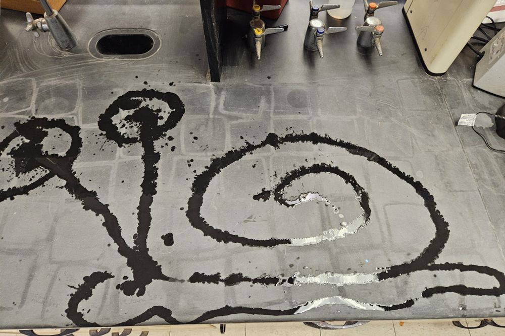 Black counter top with a SpongeBob like snail drawn with ethanol (clear liquid)