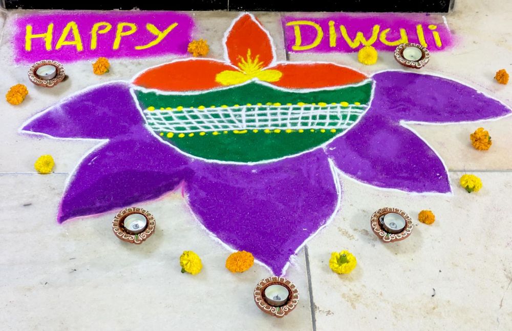rangoli with text "Happy Diwali" in front of a pillar at the entrance to our building