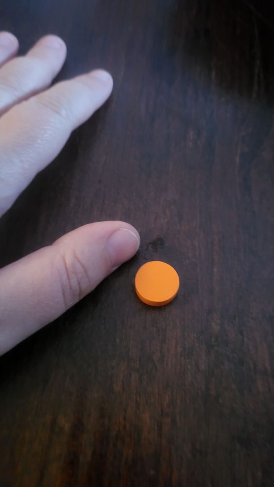 A small orange wooden disclaimers, about 1.5 cm across. 