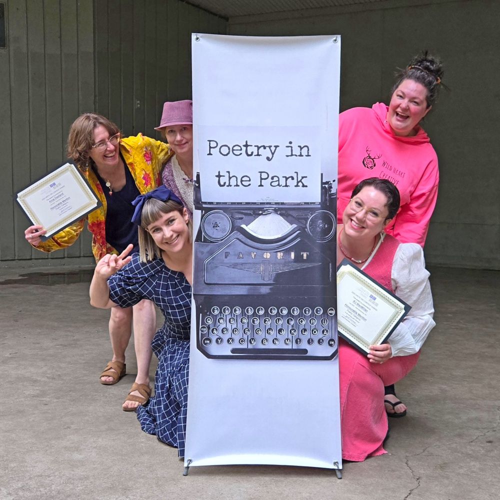Poets posed behind Poetry in the Park Banner on bandshell stage:
Anna Eastland, Janet Kvammen, Jessica Lee McMillan, Chelsea Comeau, and KJ MacMillan.
