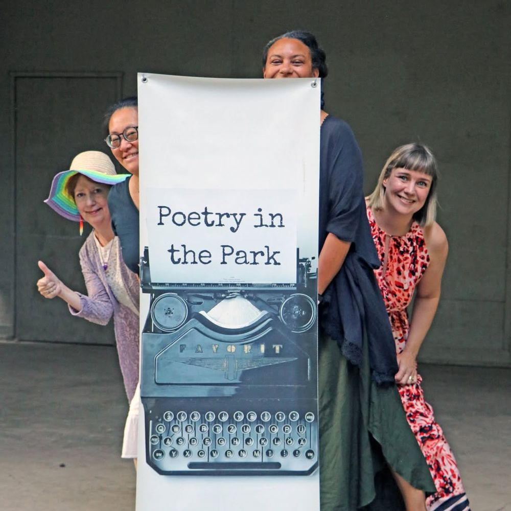 Photo: Poets on stage peeking from behind vertical Poetry in the Park banner. Janet Kvammen with Rita Wong on left and Cecily Nicholson with Jessica Lee McMillan on right.