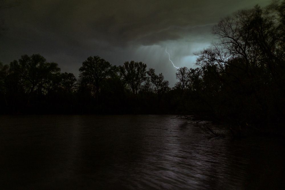 A lightning strike that illuminated a cloud of rain over a cove. 