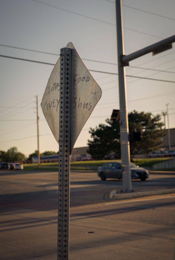 A photo of the back of a street sign that reads cloths food money shoes 