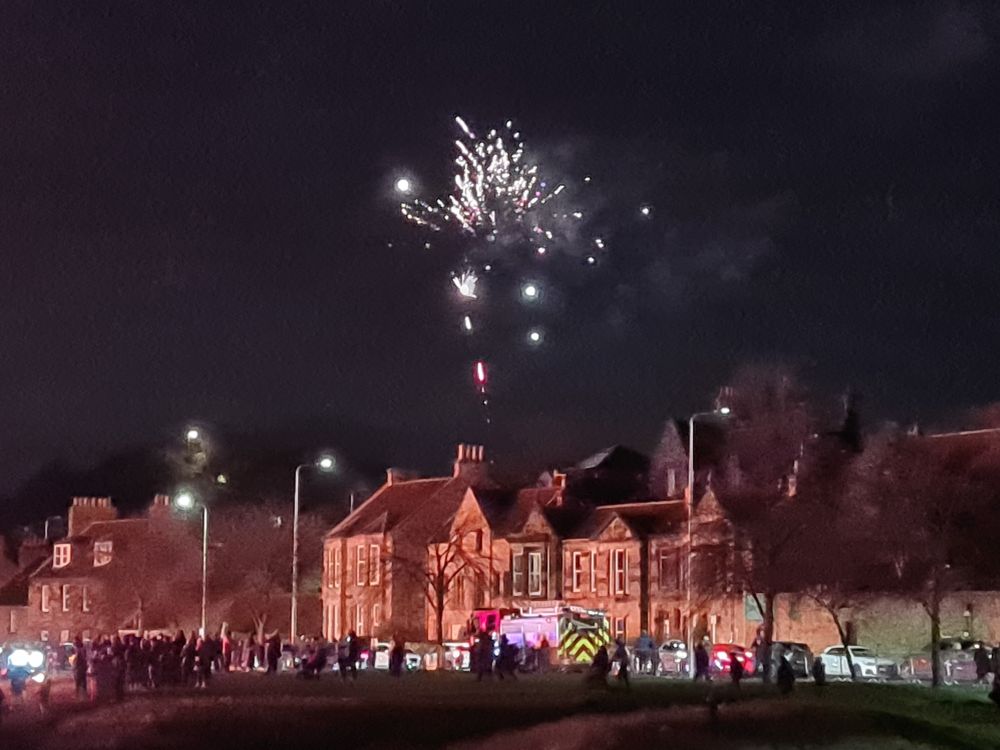Stone houses lit up with fireworks exploding above in the night sky