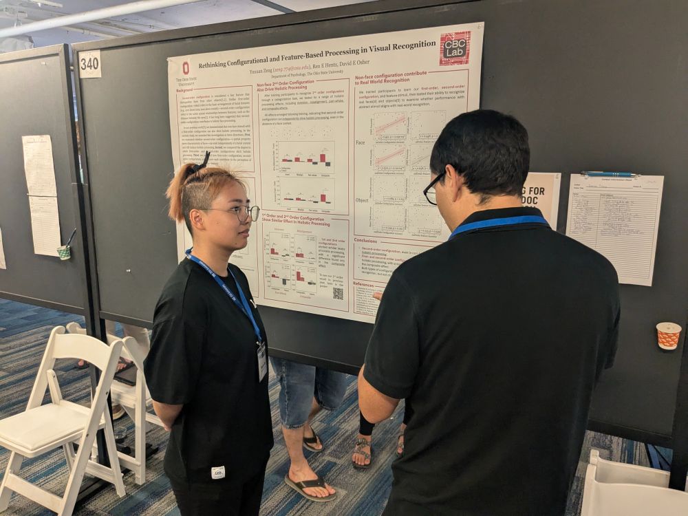 Yuxuan chats with a fellow VSS attendee in front of her poster, entitled "Rethinking configurational and feature-based processing in visual recognition".