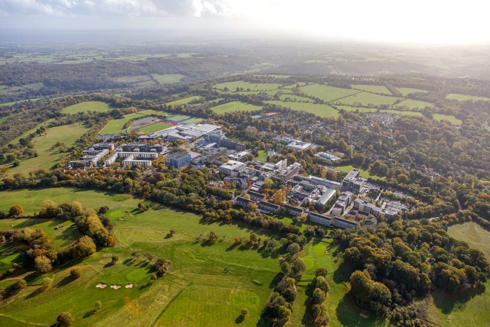 An aerial view of the University of Bath campus, showing buildings, sports facilities and surrounded by countryside