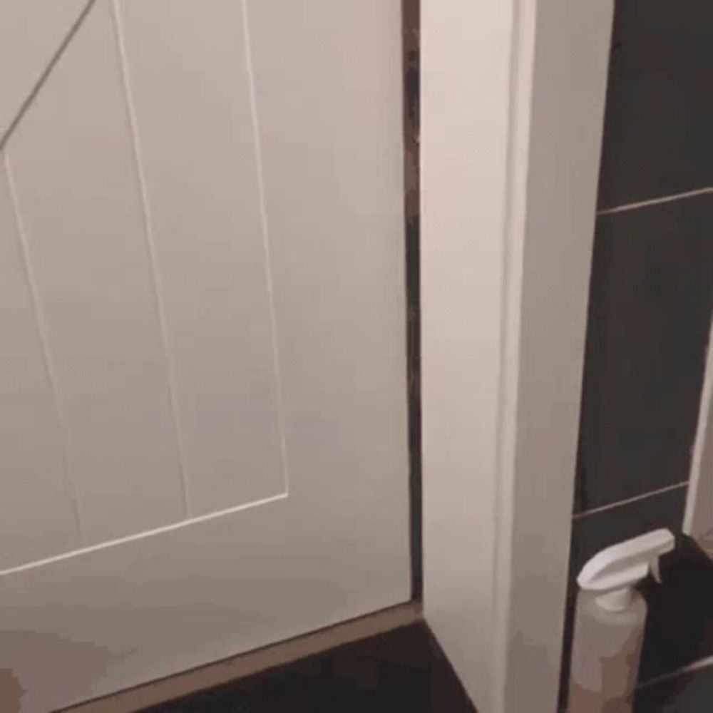 a spray bottle sits next to a white door in a bathroom