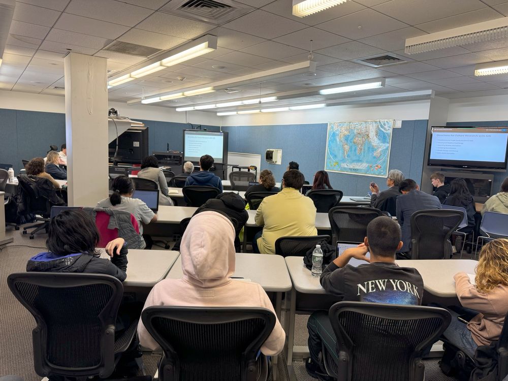 A full room of students and staff listening to the presentations.