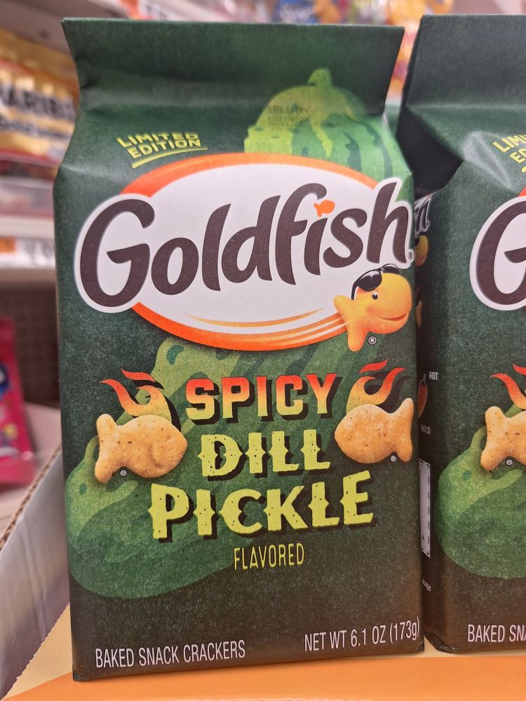 Package of limited edition spicy dill pickle flavored goldfish crackers. The package is deep green and the little goldfish cracker silhouettes on it have flames rising from them.
