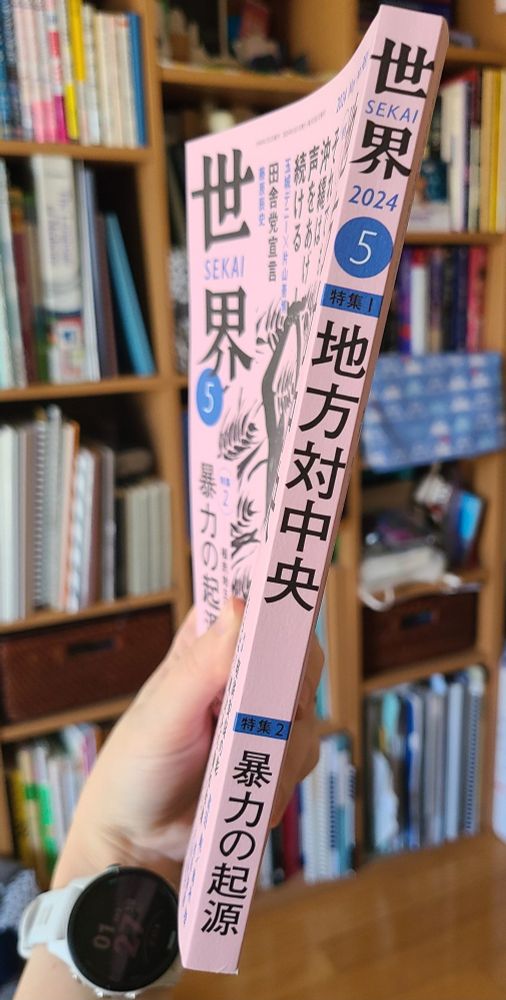 Kazen holding a copy of Sekai to show how slim it is - there are 300 pages and it's only 12 mm/half an inch thick.