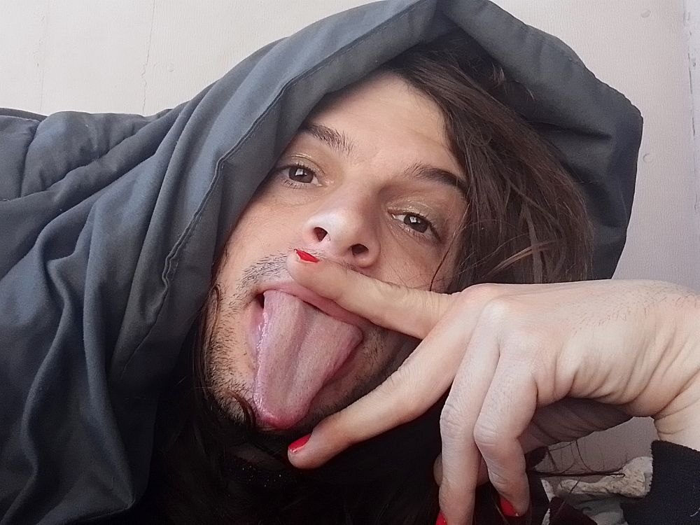 Miu is doing the provocative gesture sticking out her tongue between her two fingers, nails are a bright red, they are covered by their blanket