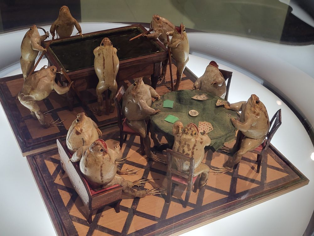 Taxidermied frogs playing poker and singing around a piano