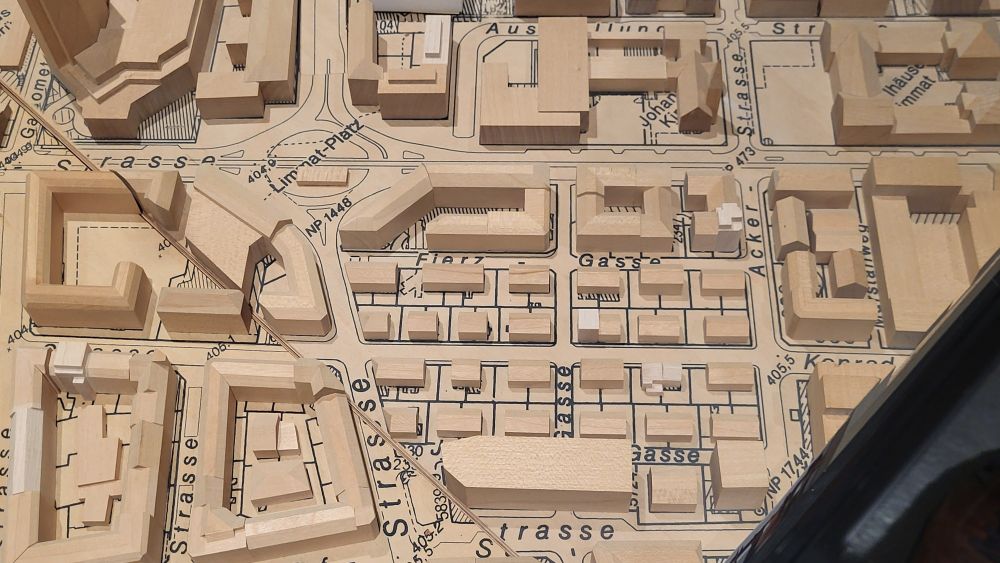 A dozen blocks of a wooden city model showing small and large buildings. Even tiny courtyard buildings, roof slopes, after-construction elevator additions, side sheds are shown.