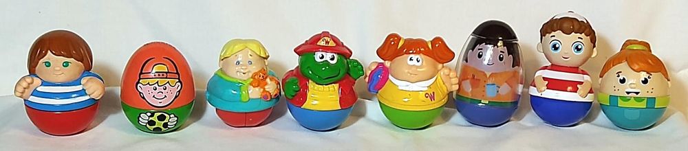 Eight Weebles figures from 1989 to 2023. From left to right:
Highway (1989), brown hair, blue eyes, blue and white striped shirt and red bottom, molded hair and hands
Soccer player (1996), egg with red top and green bottom with blond haired boy in backward red ball cap and hands around soccer ball stamped on
Boy with bear (2001 "They Roll Too"), blond hair, teal sweatshirt with green trim, red bottom, holding orange teddy bear
Tooey Winkington (2004 "Weebleville"), green turtle in yellow shirt, blue bottom, red jacket, and red firefighter hat
Jill (2006 "Storybook World"), redhead with pigtails in yellow dress and green bottom, carrying bucket of water
Dad (2010), clear egg with insert showing black hair, orange button-down shirt, green belt, and blue bottom, holding coffee cup
Willie (2016 "Wonder Club"), boy with brown hair, blue eyes, backward red and white ball cap, red and white striped shirt, and blue bottom with white stripes
Harper (2023), girl with ponytail, freckles, green shirt, and blue overalls with pocket