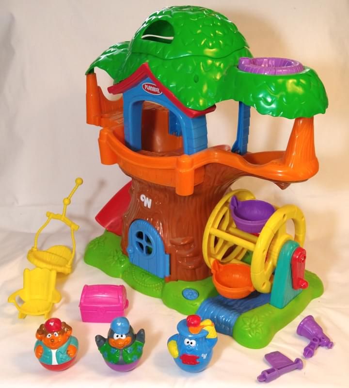 Weebles Weebly Wobbly Tree House playset (2005). Main unit is brown on a green base with a yellow water wheel with a red crank, with an orange second floor with blue walls and a green treetop layer. Includes chair, treasure chest, flag, telescope, and Bumpus (sheepdog), Pendleton (penguin), and Cookie (oven) figures.