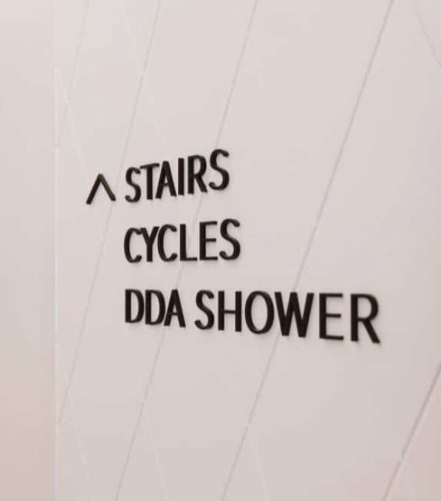 Signage in a building indicating the location of a shower accessible for people with disabilities which describes it in inappropriate technical language as a 'Disability Discrimination Act' (DDA) Shower.