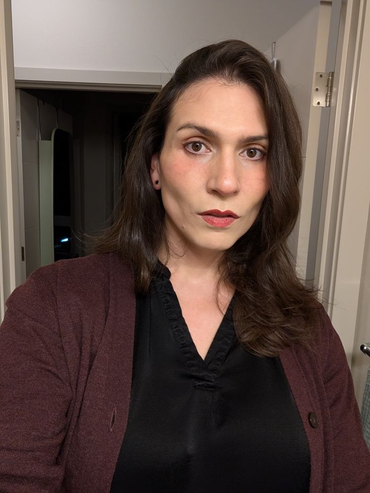 Selfie of me with a side part and curtain bangs, hair to my collarbone 