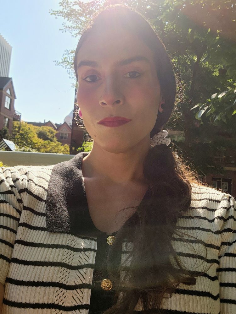 Me in a black and white striped knit top with gold buttons. Sitting in the park before work.