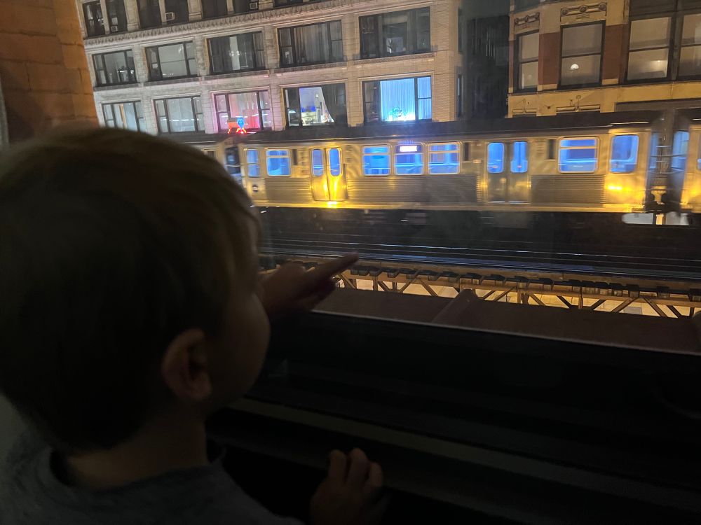 5 year old pointing at a passing elevated train out the window in Chicago