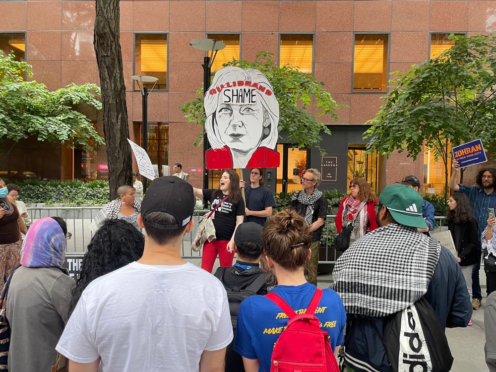A group of protestors holding a cutout of Gillibrand’s head with the word SHAME