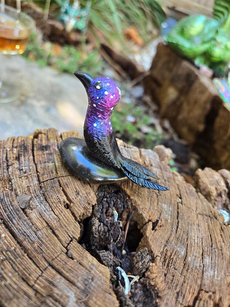 A crow made from clay with a galaxy pattern on its feathers