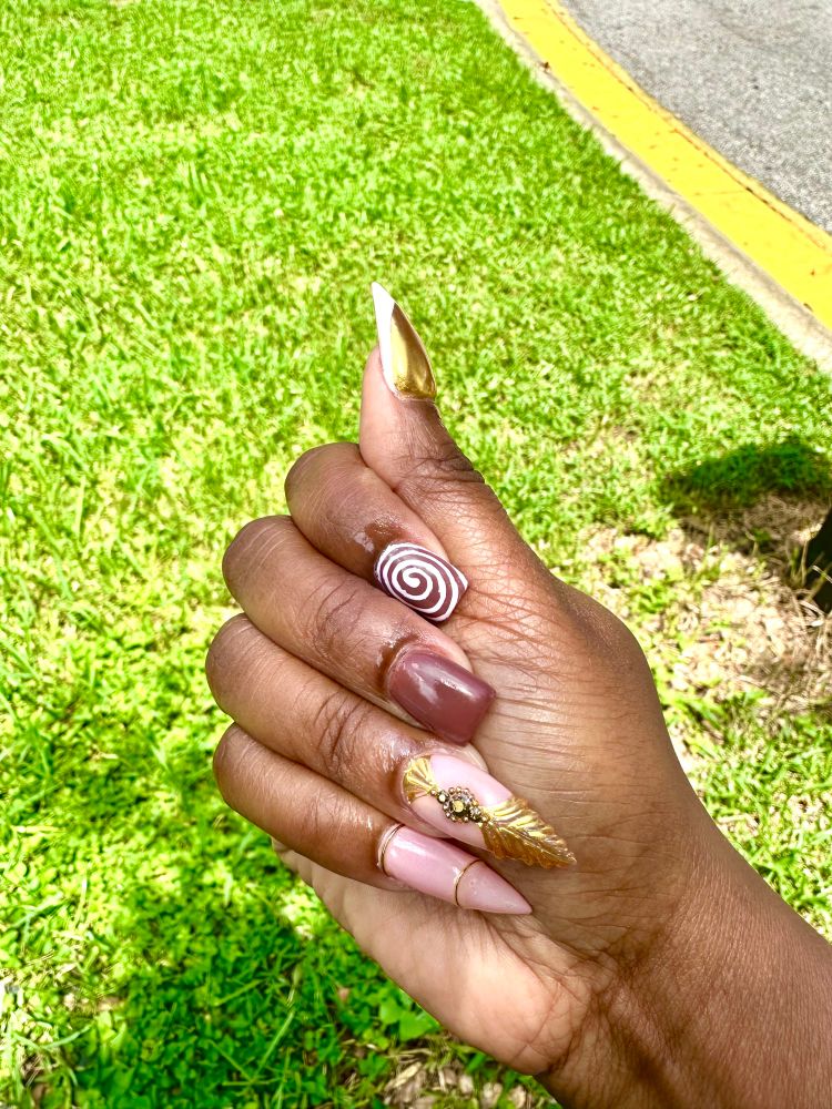 A mixture of stiletto and square shaped nails that are brown, nude and gold. 