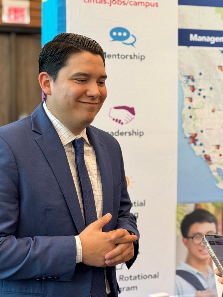 Man in navy blue suit smiling. 