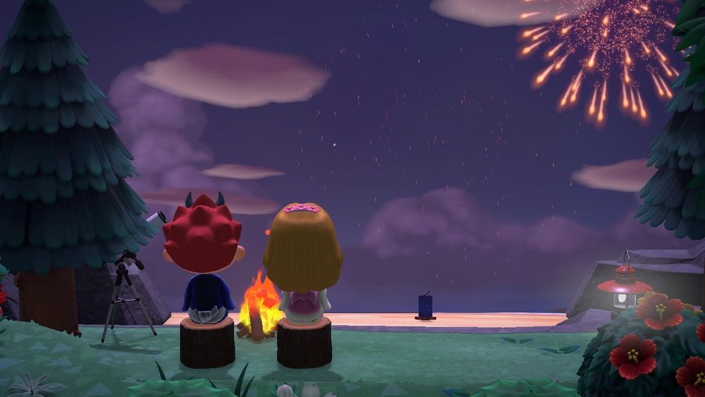 the same two residents sitting on log stools in front of a bonfire, picture taken from behind. the beach is visible in the background, the sun has set and there's firework(s) in the sky. the shot I'd framed by two pine trees and one bush