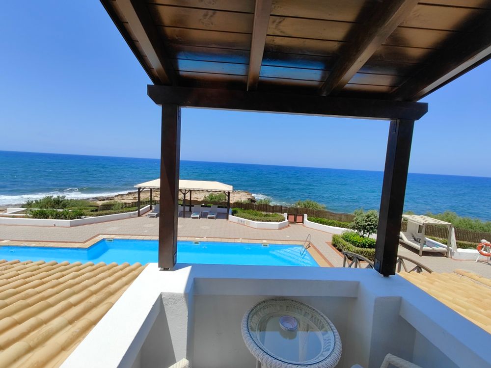 Blick vom Balkon aufs Mittelmeer bei blauem Himmel. Ein Pool ist sichtbar.