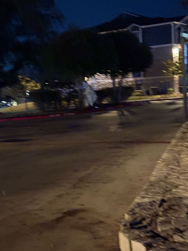 A plain white figure stands across the parking lot from you in the dark shadows. He has a sign that says “Now Hiring”..?