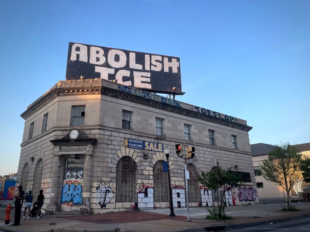 Abolish ICE graffiti art on billboard atop old bank building in Baltimore, Maryland (North Ave and Charles Street). 