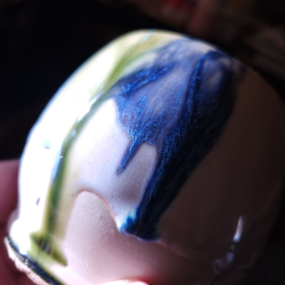 Drippy glazes in bright sunlight. Dark green and blue drips on white glaze 
