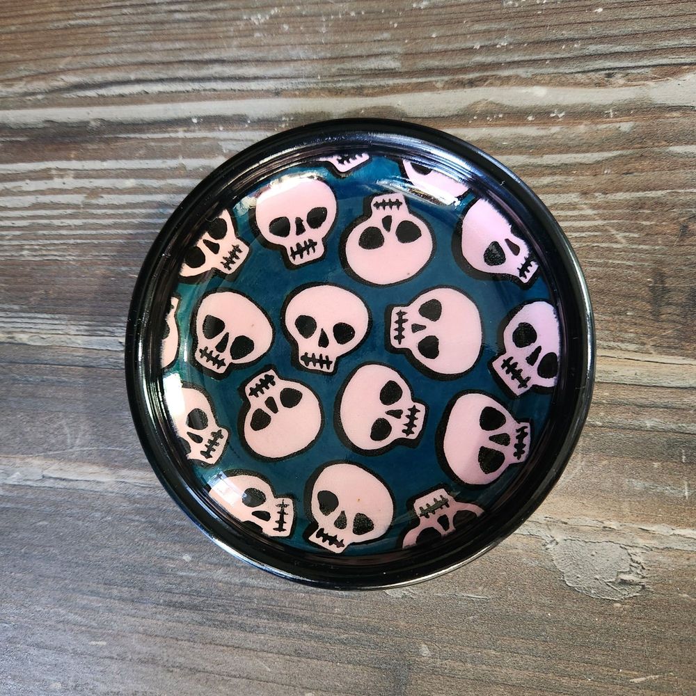 Full view of small fish with pink skulls & turquoise background with black rim