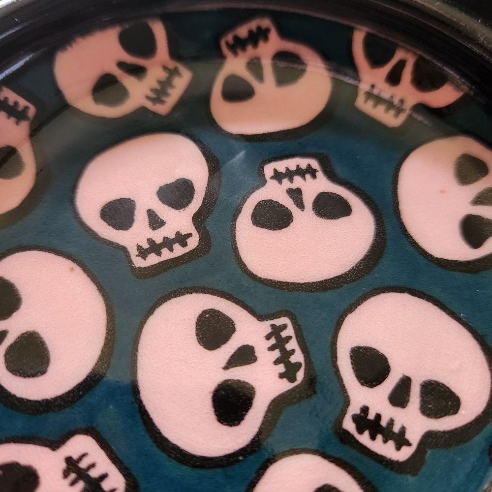Detail view of small fish with pink skulls & turquoise background with black rim